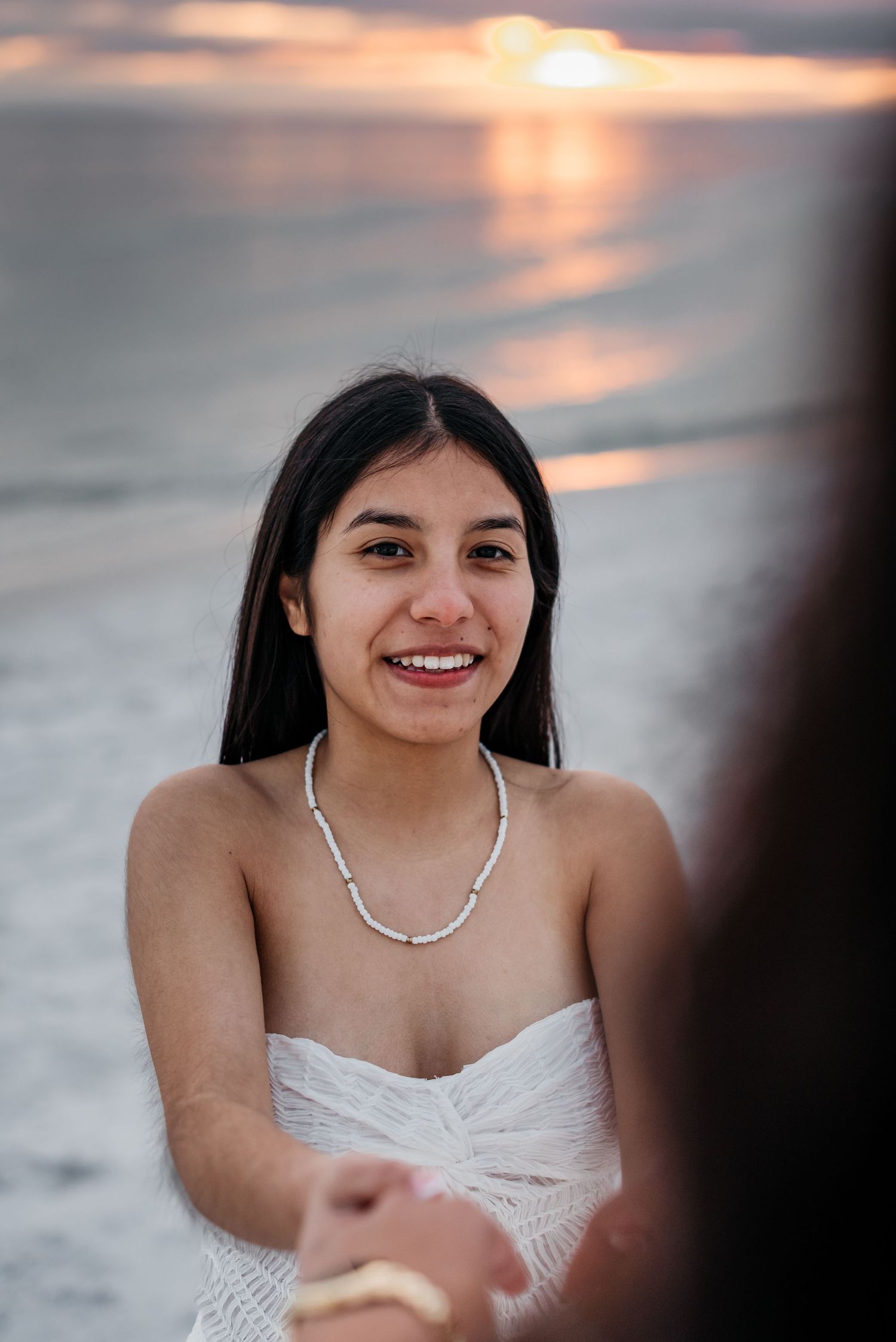 A beachside portrait with a sunset reflection on the ocean.