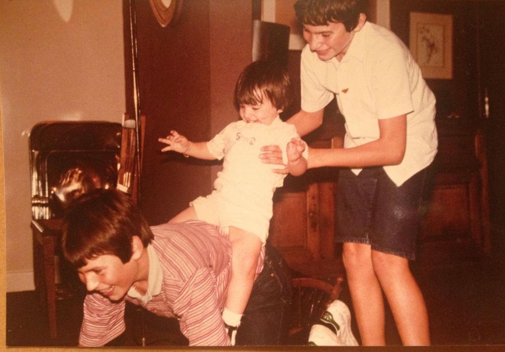 Vintage family photo showing playful moment in front of fireplace.