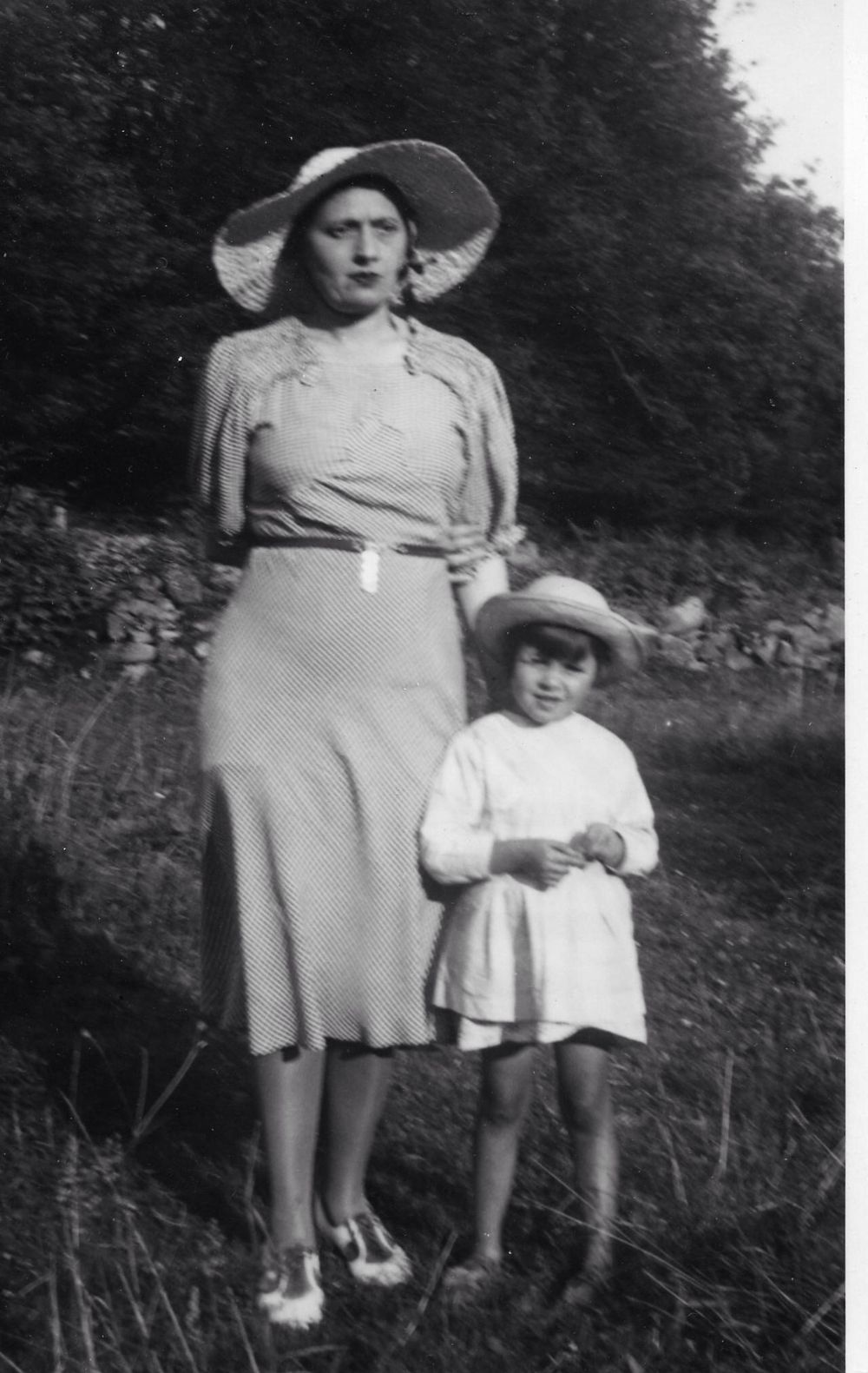Vintage black and white photo from the 1940s showing an adult and child in summer attire standing outdoors.