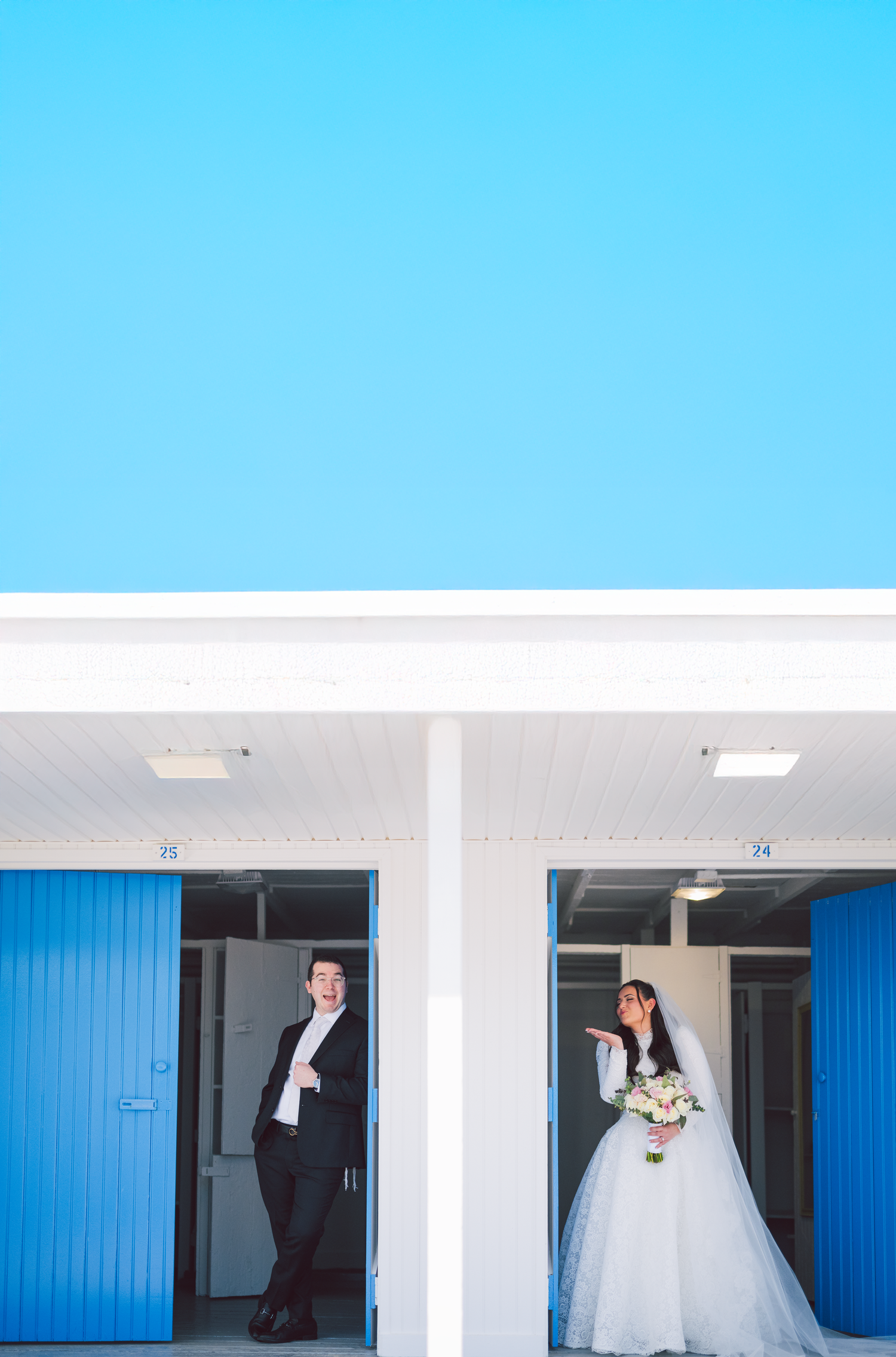 Modern wedding venue hallway with bright blue doors and white walls.