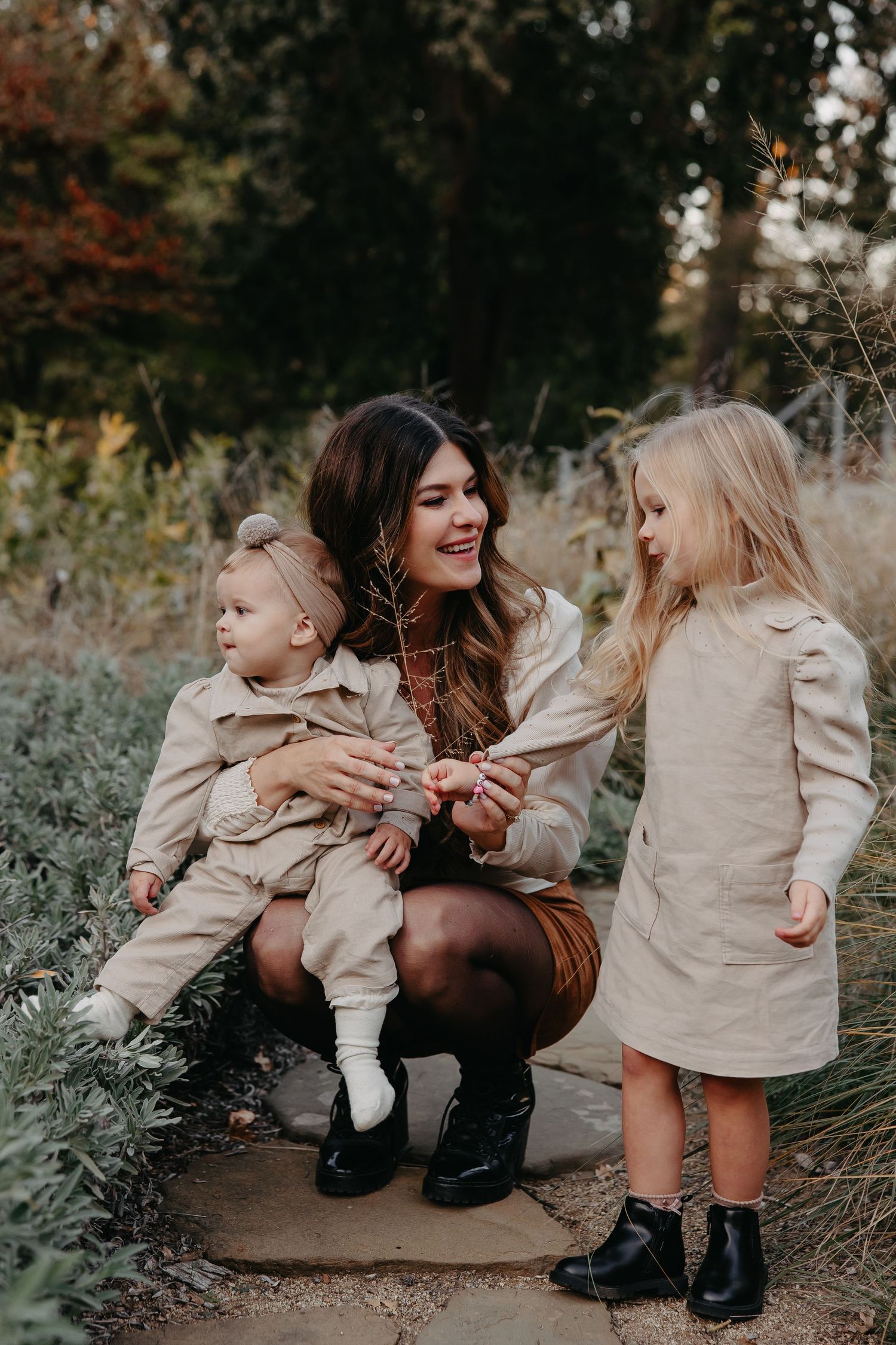 Family shares a tender moment outdoors in neutral-toned coordinated outfits during autumn season.