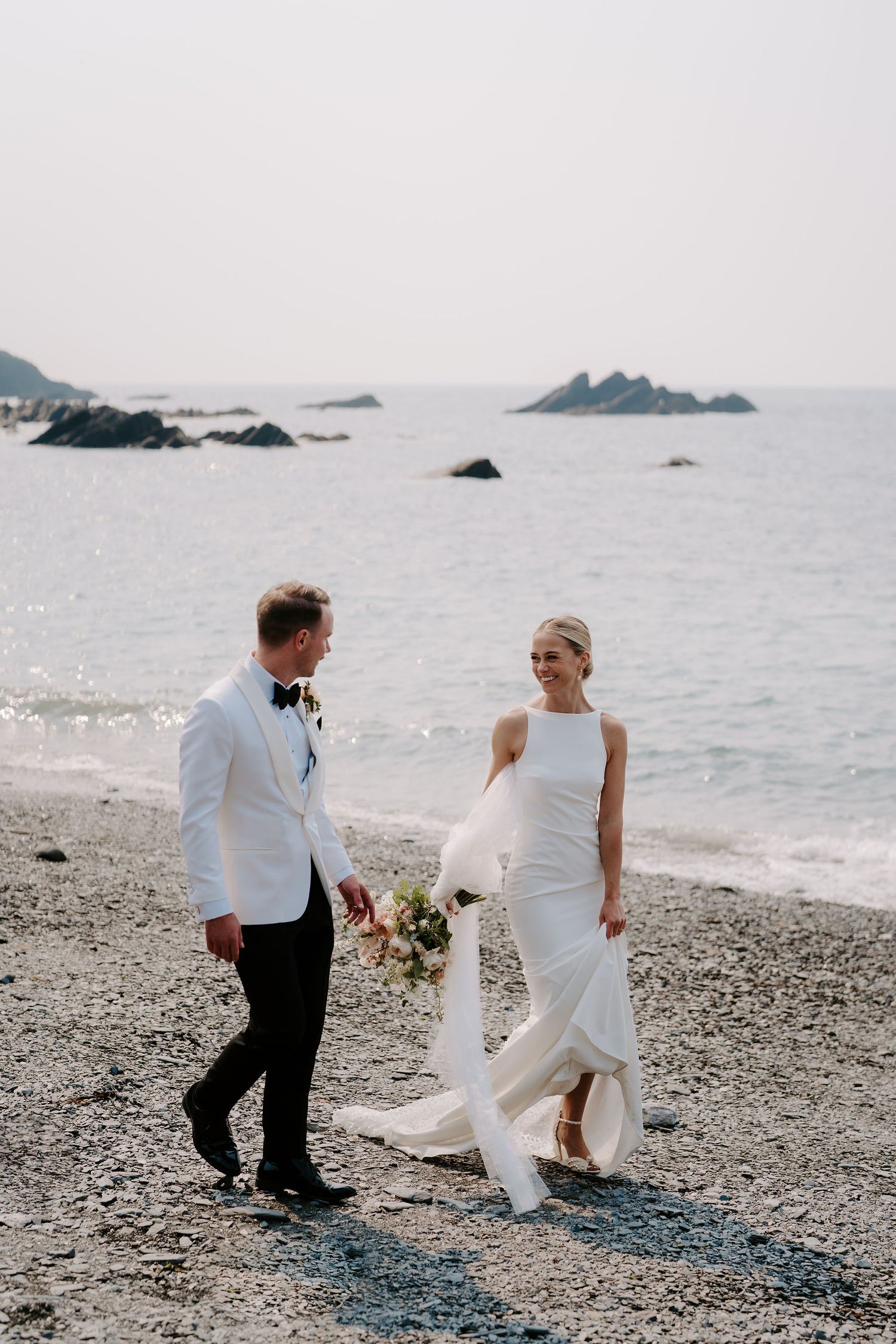 Bride and Groom walking along beach at Tunnels beach wedding venue in north devon