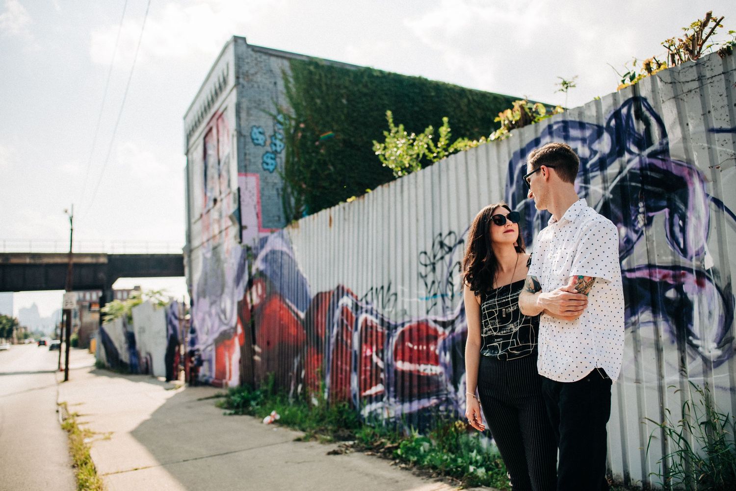 Couple embracing near colorful graffiti wall on urban street.