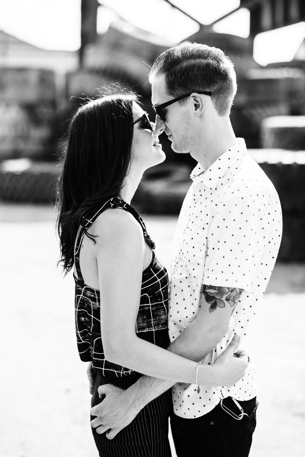 Black and white photo of couple almost kissing outdoors.