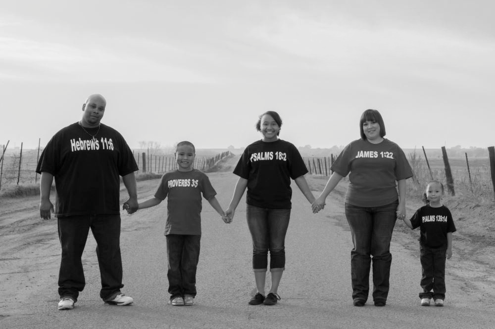 A family of five holding hands while standing in a line.
