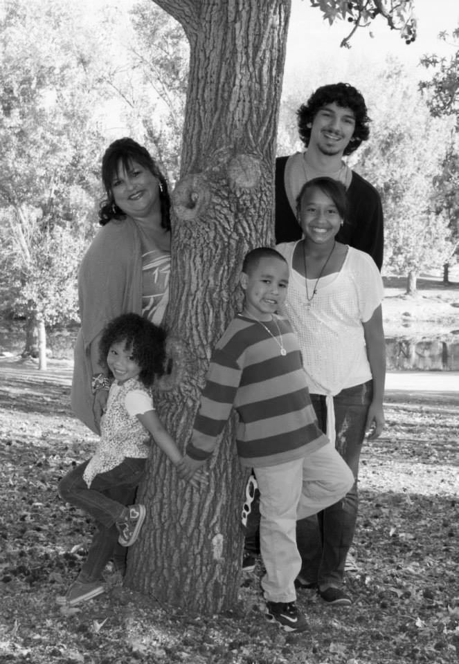 A grandmother poses with four of her grandchildren in a park.