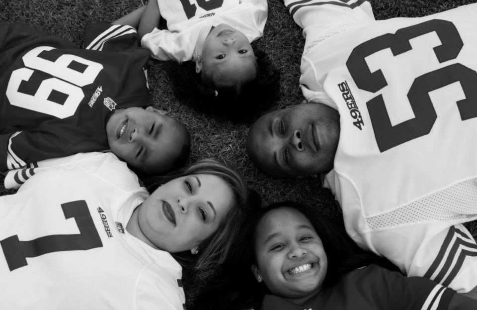 A family of five wearing 49ers jerseys lay in a circular pose.