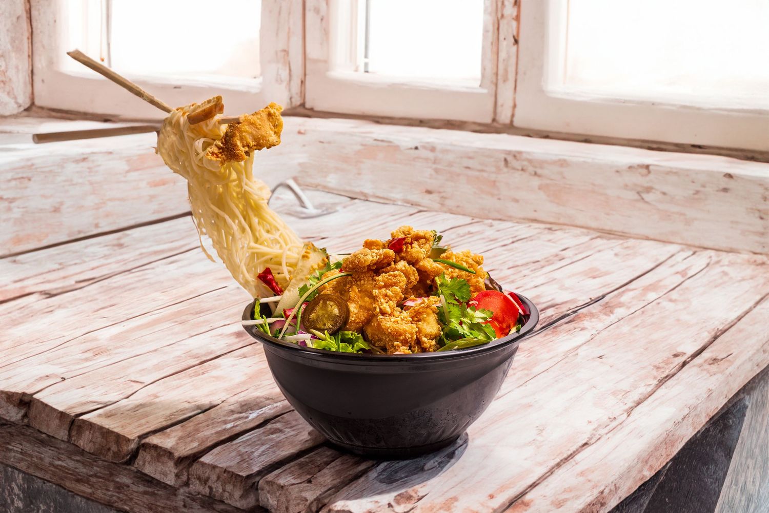 Colorful Buddha bowl with grilled chicken, avocado, greens, roasted vegetables, and dipping sauce on a white plate.