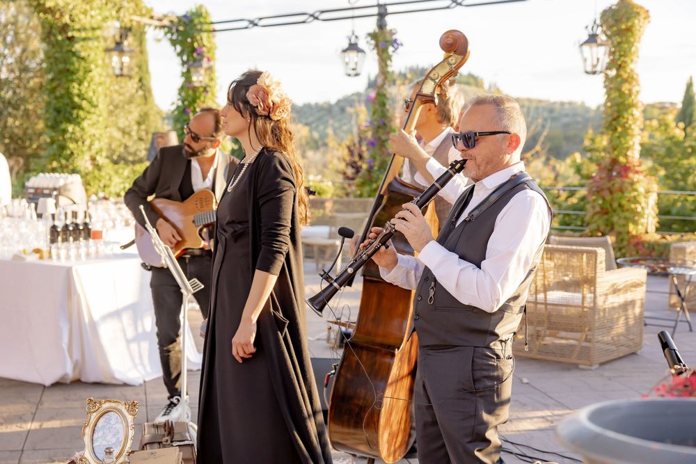 Live jazz band performing outdoors at an elegant wedding reception, featuring a bassist, vocalist, and clarinetist.