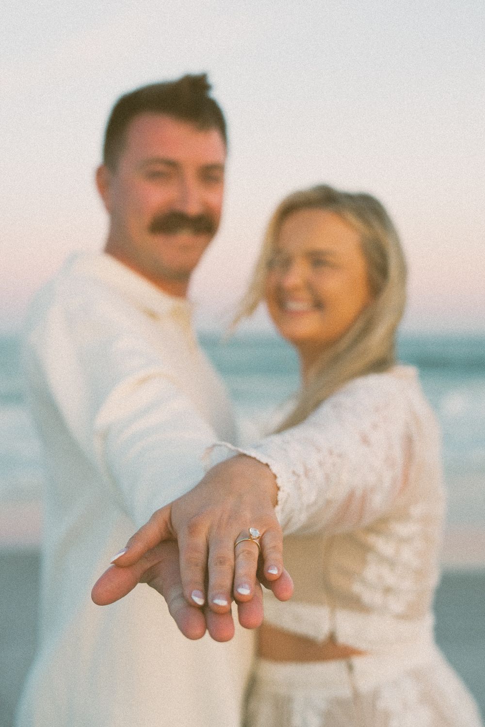 Engaged couple - Wrightsville Beach at sunset showing off diamond engagement ring. Wilmington NC Photographer