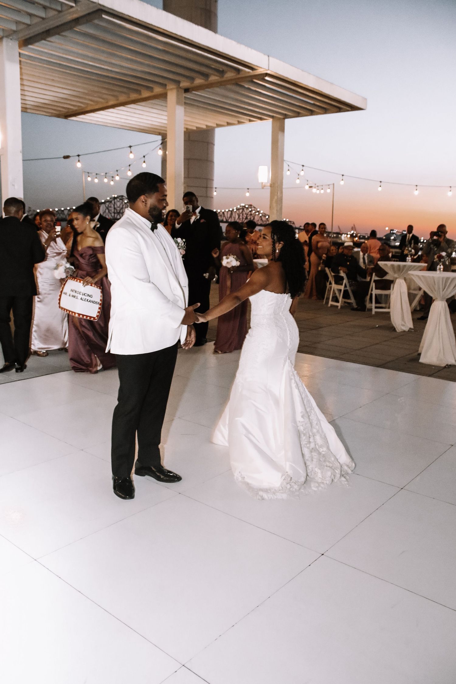 Wedding couple sharing their first dance on an outdoor rooftop venue at sunset.