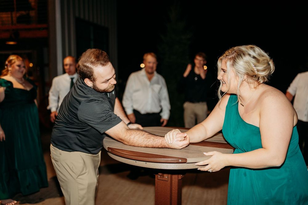 Couple holding hands and dancing together at an elegant wedding reception with guests in the background.