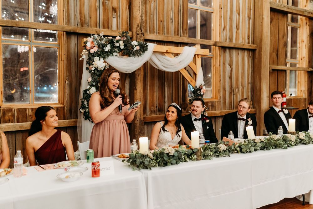Bridesmaid delivers a heartfelt speech at a rustic barn wedding reception.