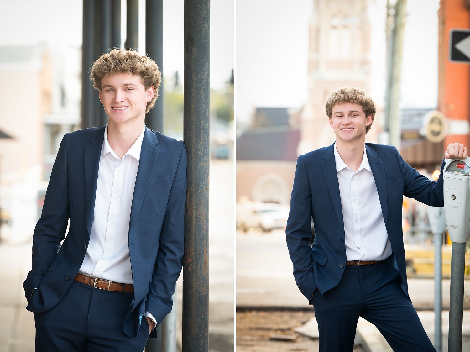 Young man in navy suit and white shirt smiling confidently outdoors in an urban setting for senior portraits.