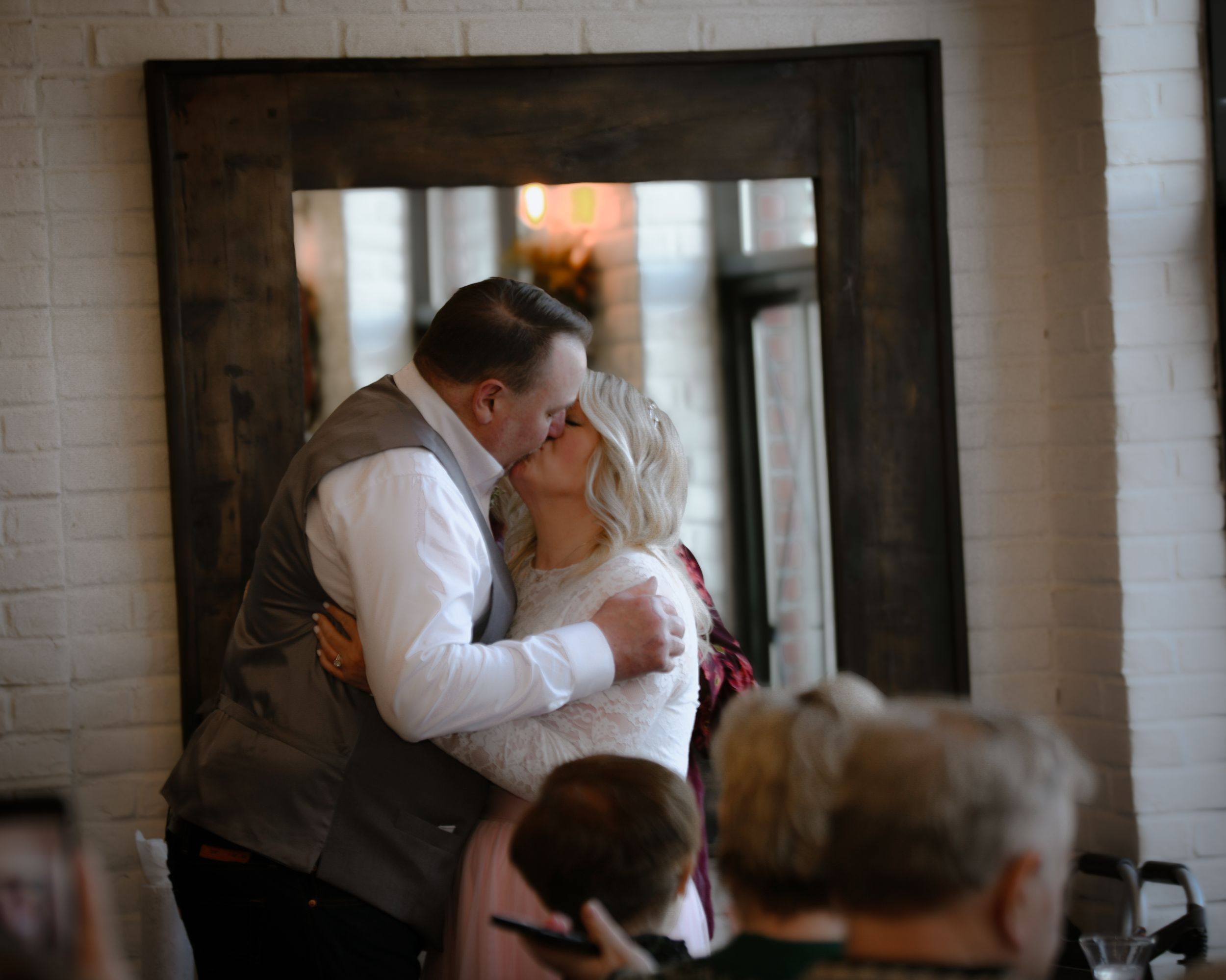 Couple sharing a romantic first dance kiss at their wedding reception in a rustic venue.