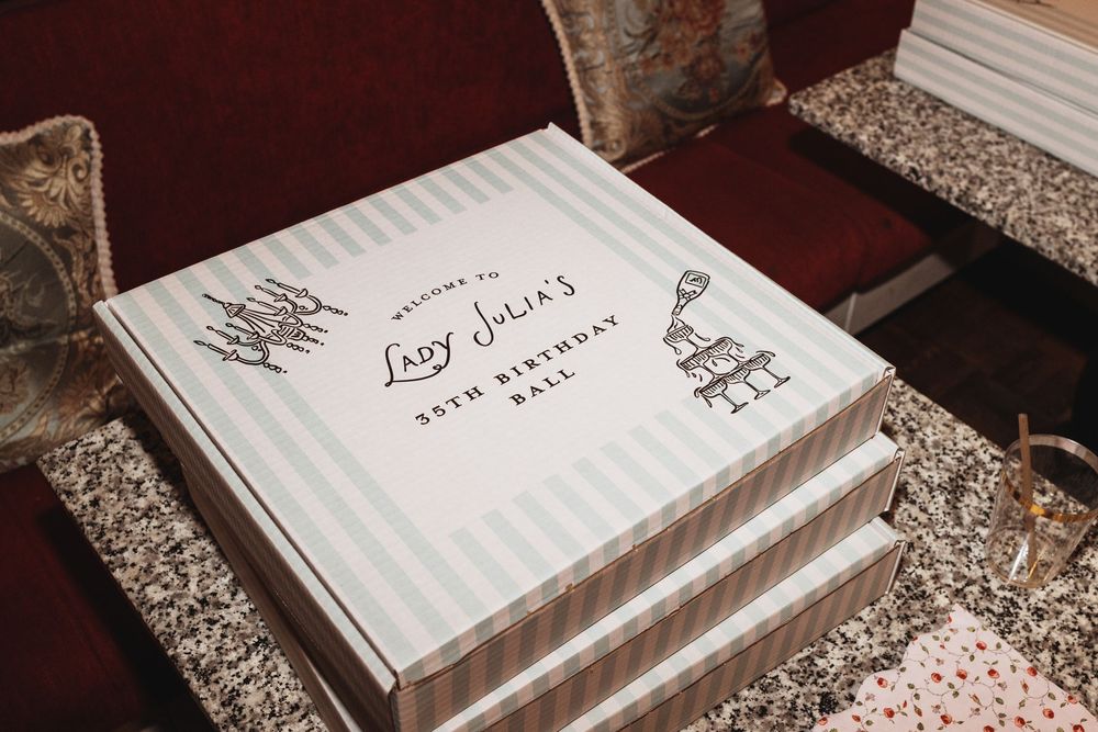 Elegant striped gift box for Lady Julia's 35th Birthday Ball, featuring decorative black text and illustrations on white.