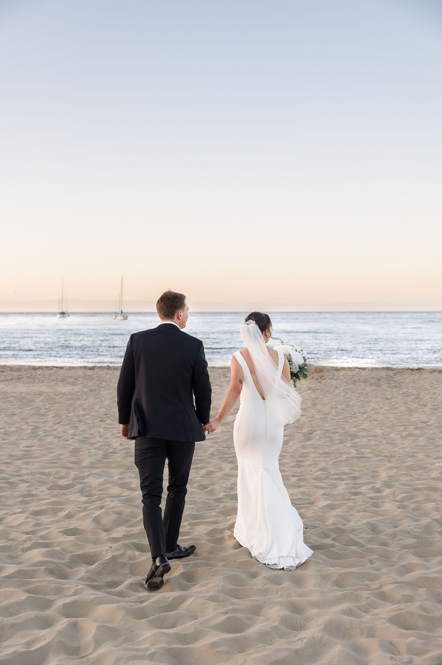 Elegant outdoor wedding reception beside a pool at a Spanish-style villa with lush greenery and guests dining.