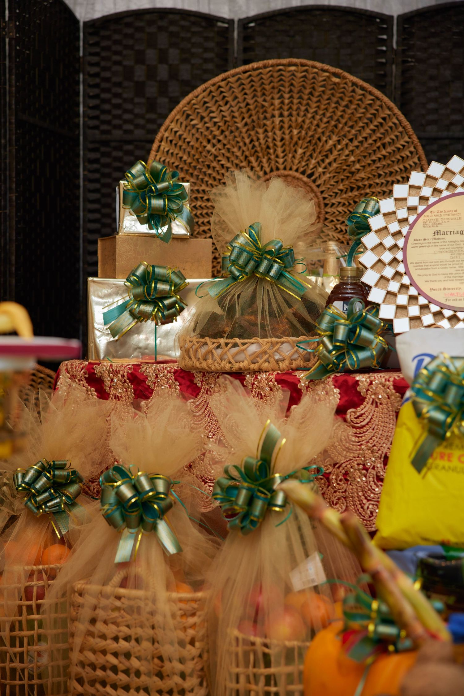 Decorative gift baskets with green ribbon bows and tulle wrapping displayed on a lace-covered table at a festive event.