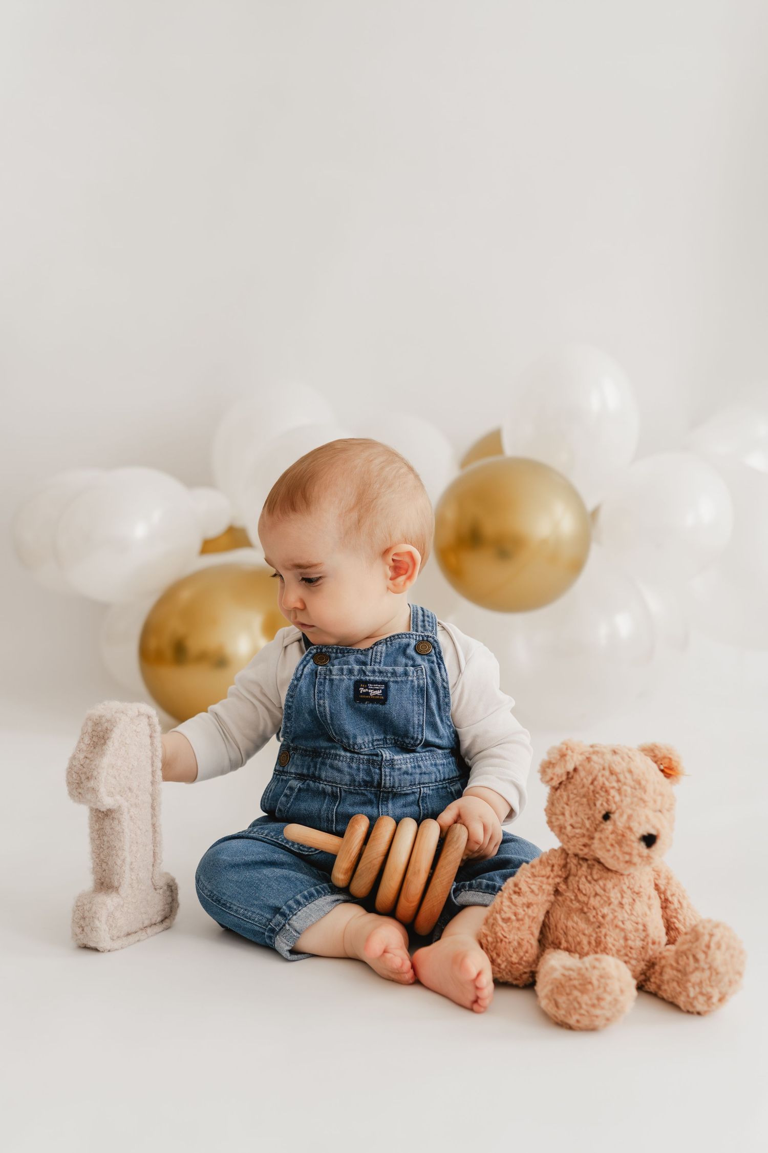 Fotoshooting zum ersten Geburtstag, Meilensteinfotos mit Luftballons und Geburtstagsdeko vom Geburtstagskind mit Teddybär