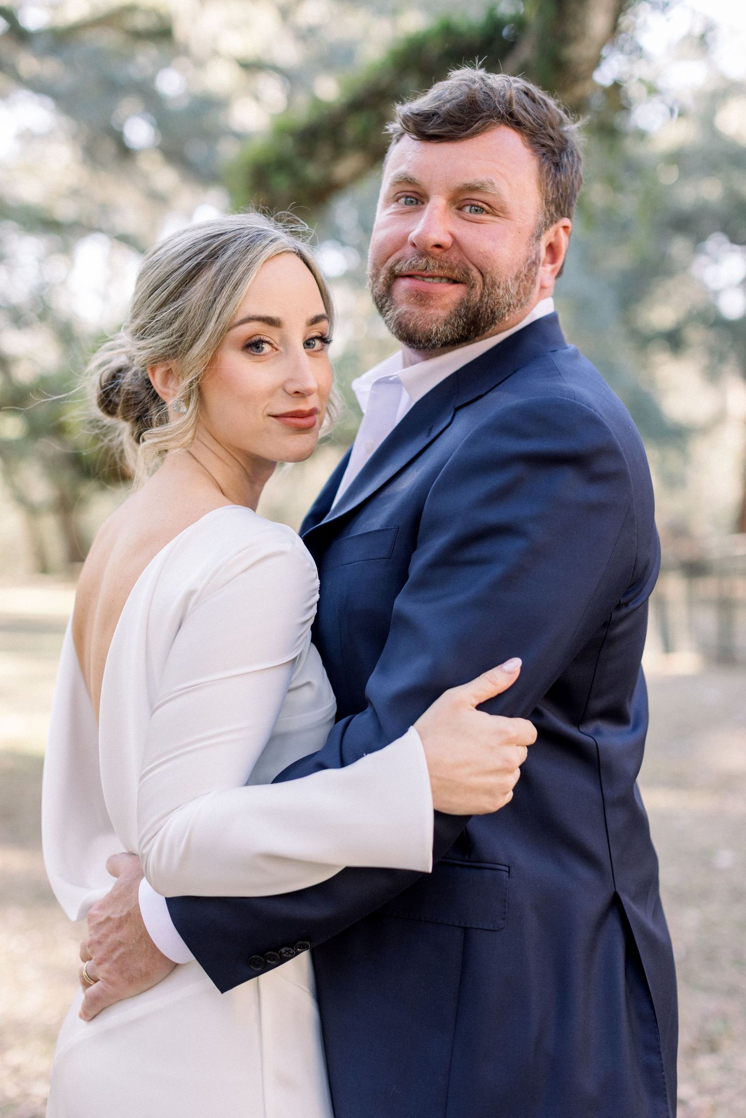 A groom and bride smiling at the camera in a lowcountry wedding photo in Beaufort, South Carolina while framed by mossy oak trees.