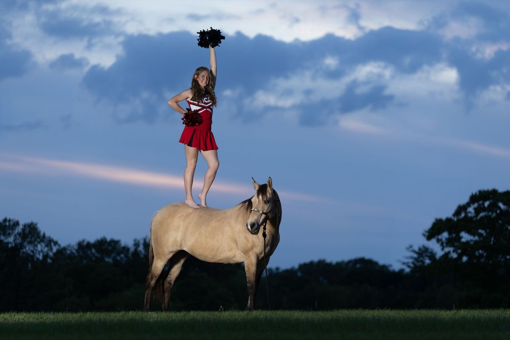 Cheerleader standing on the back of a horse at sunset, epic equestrian senior portraits, unique equestrian portraits with off camera flash