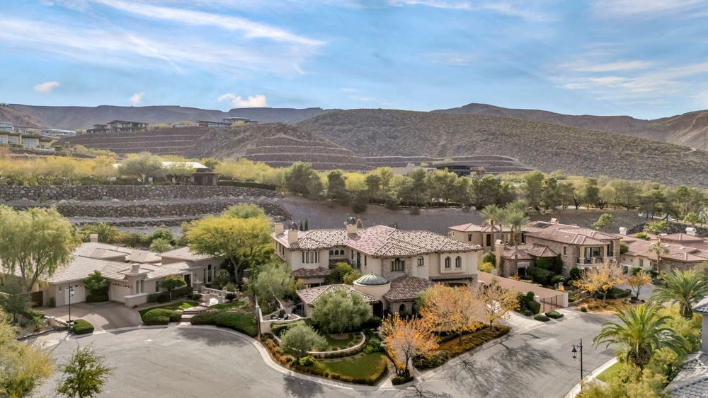 Upscale Las Vegas estate homes with tile roofs surrounded by mature landscaping and mountain scenery.