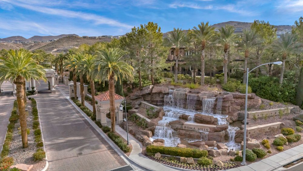 Scenic community waterfall feature flanked by tall palm trees with desert mountains in background.