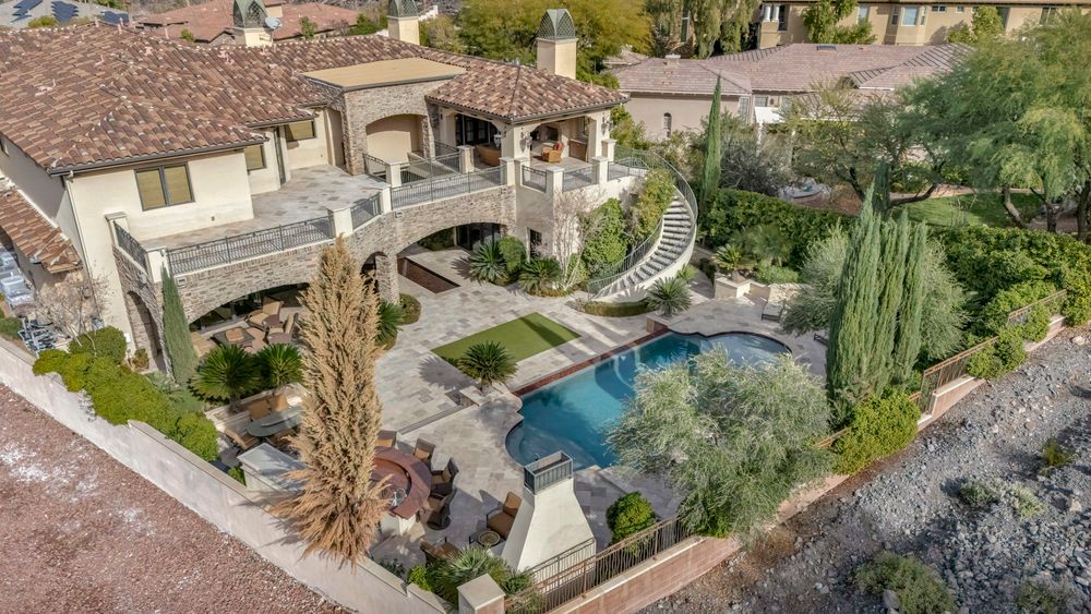 Aerial view of luxury estate with pool, spiral staircase, and lush landscaping in Las Vegas.