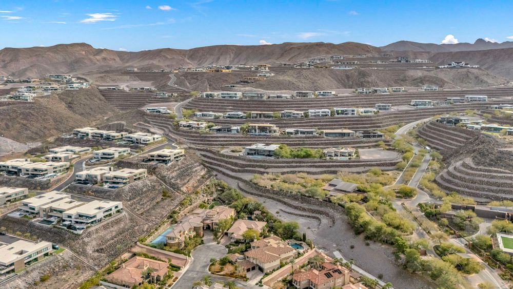 Aerial view of terraced hillside development with winding roads near a desert wash in Las Vegas valley.
