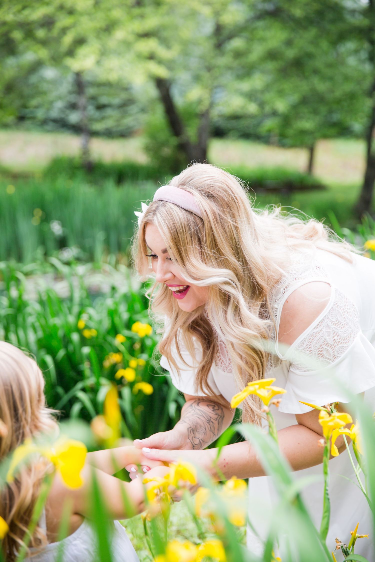 Couple in a flower field, man kissing pregnant woman wearing white dress and floral crown, maternity photo.