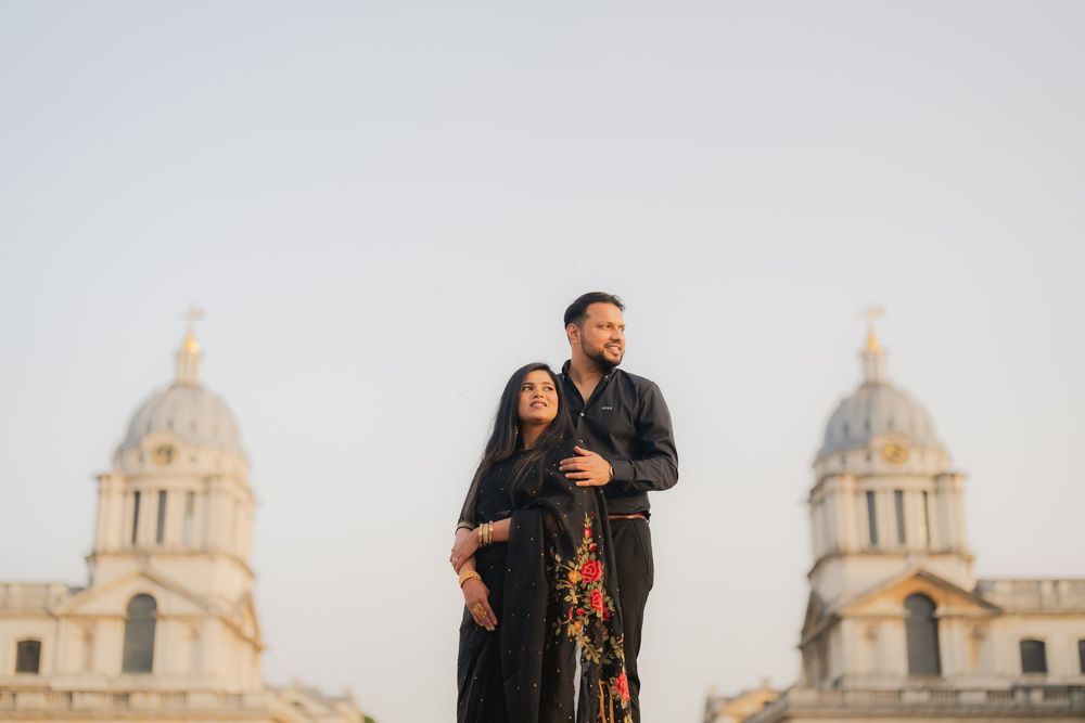 Couple in black attire posing in front of the Old Royal Naval College domes in Greenwich, London.