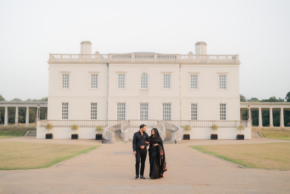 Couple in black attire posing before the Queen's House, Greenwich, a stunning white Palladian mansion.