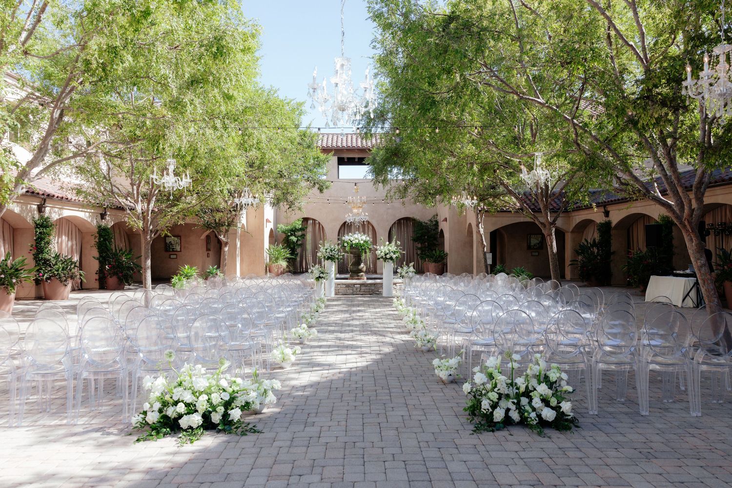 Bridesmaids holding rustic woven baskets filled with elegant white and green floral arrangements at a wedding ceremony.