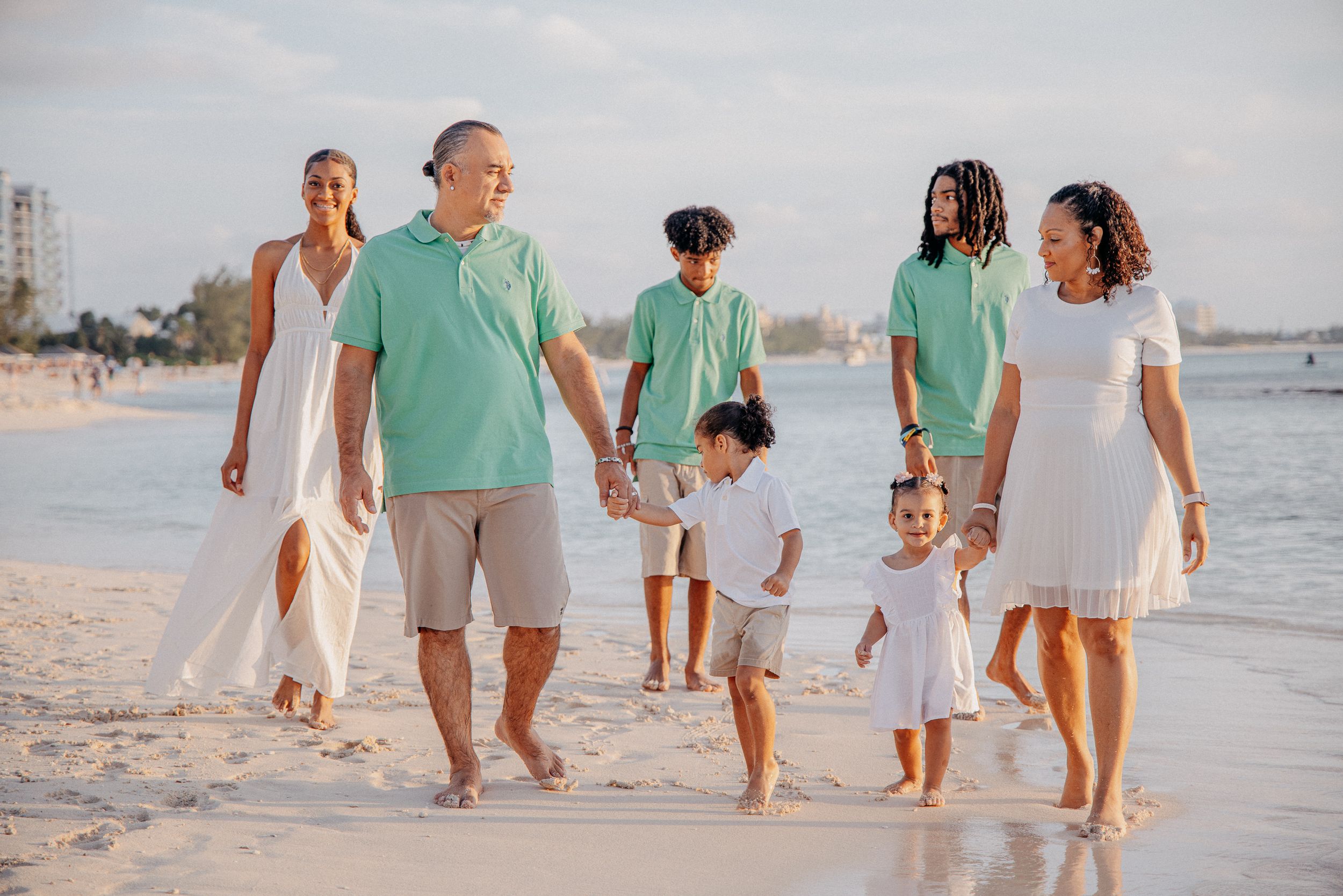 Group walking along shoreline wearing coordinated white and mint green outfits.