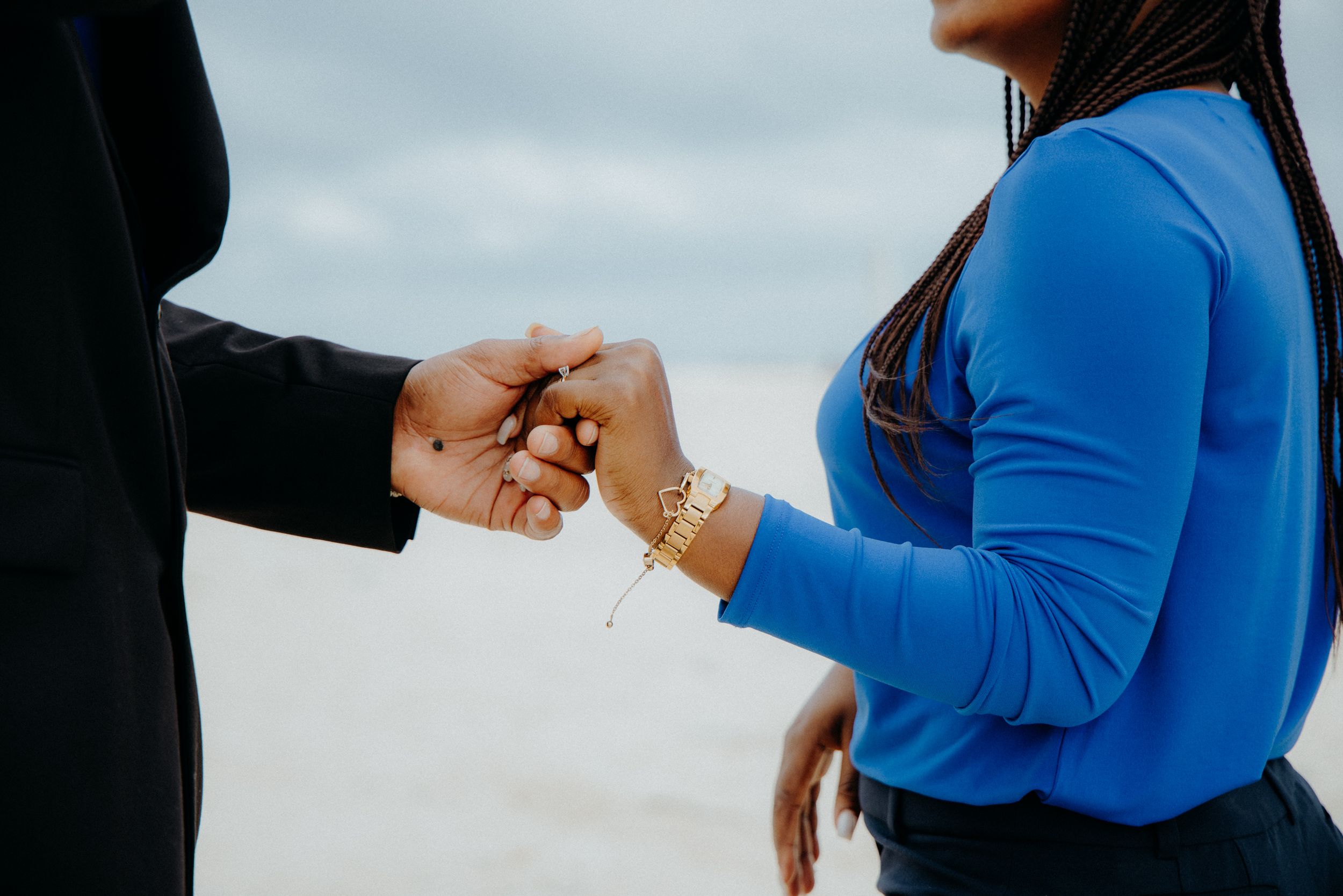 A couple in formal attire sharing an emotional moment by the ocean.