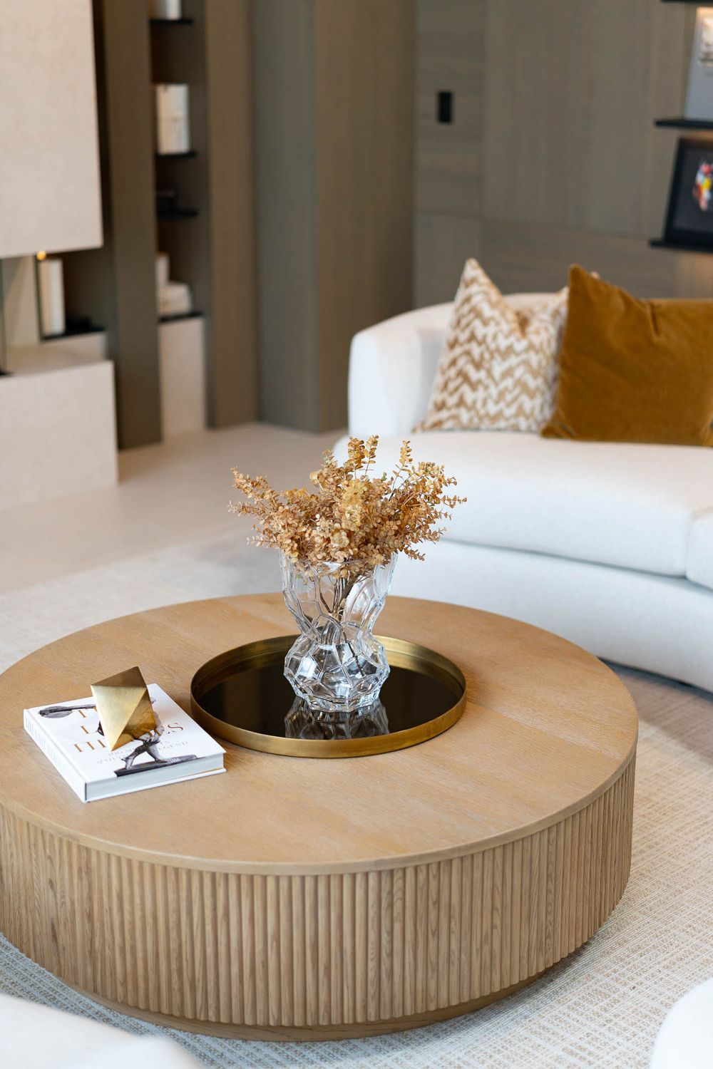 Four sequential images showing a modern round wooden coffee table with fluted sides and decorative vase styling.