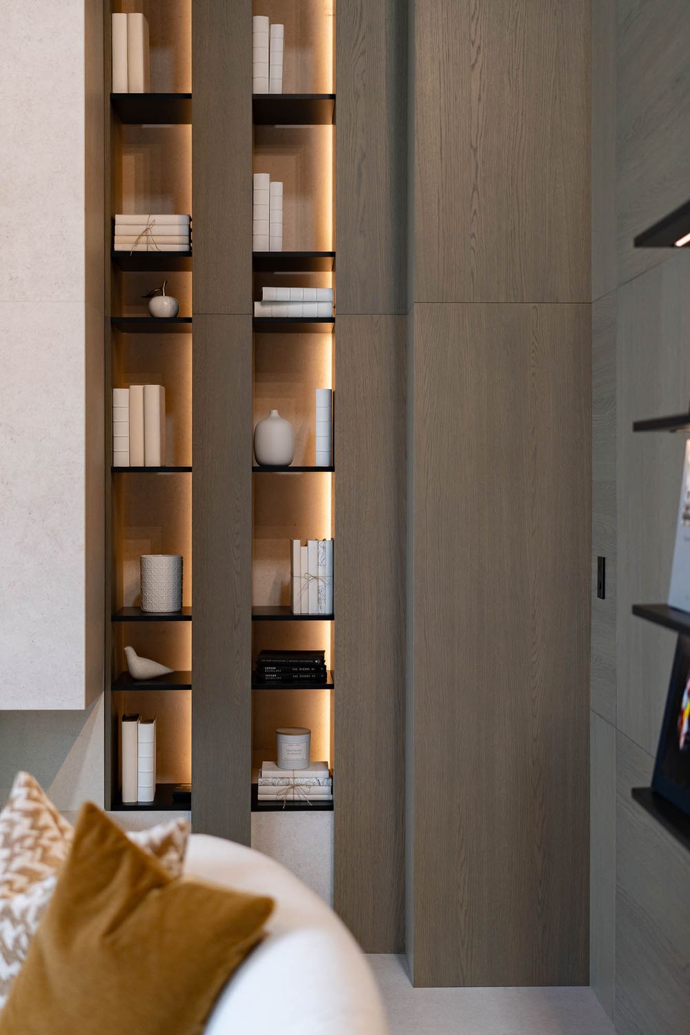 Modern built-in shelving unit with backlit display featuring white books and decorative objects.