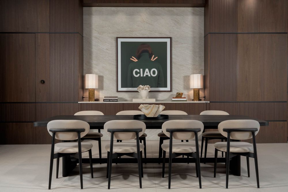 Modern dining area with black chairs and white upholstery arranged along a sleek wooden table.