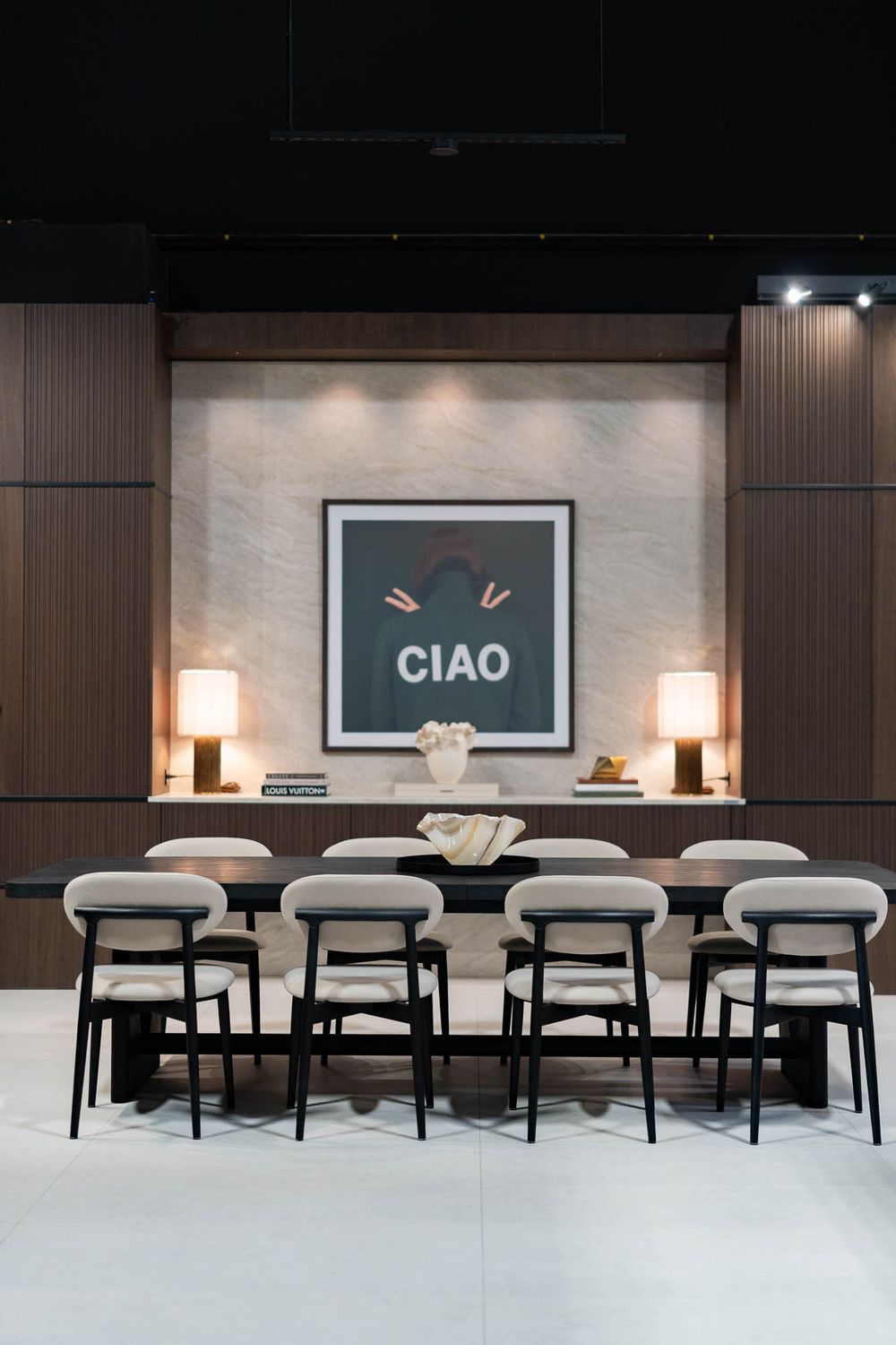 Contemporary dining room featuring dark wood paneling and a shelf with a CIAO sign and decorative items.