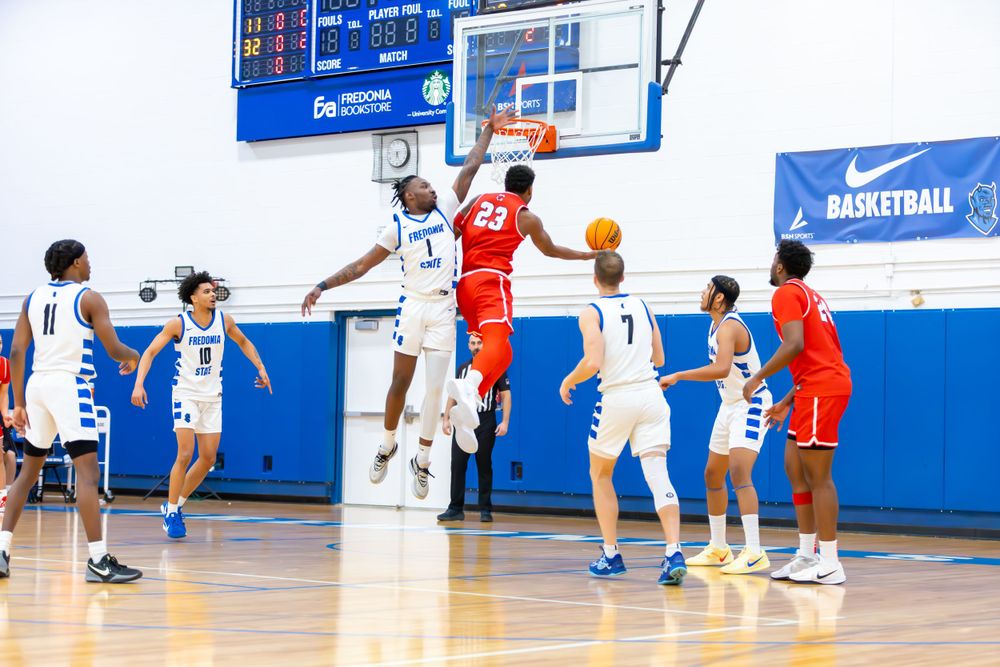 Players from opposing teams battle for position during a competitive basketball match on a bright court.