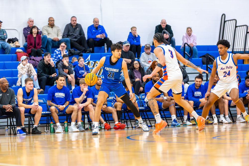 Spectators watch from bleachers during an indoor basketball game.