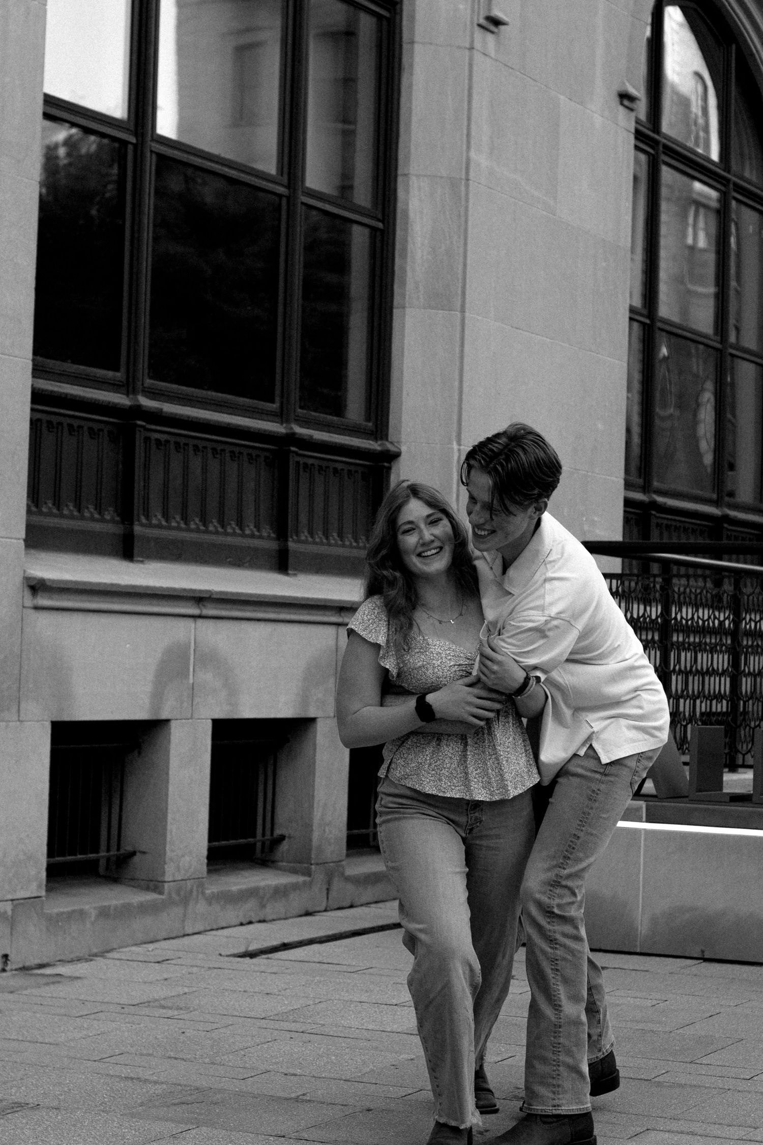 Playful black and white sequence of two people interacting outside a building.