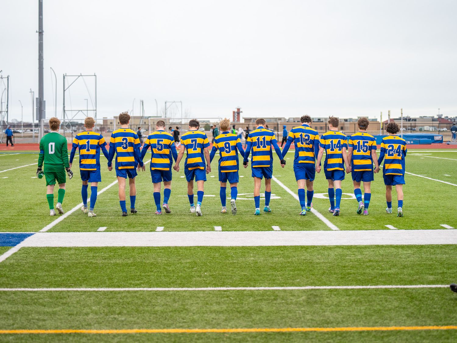 Soccer team lines up for pre-game photo in blue and yellow striped uniforms.