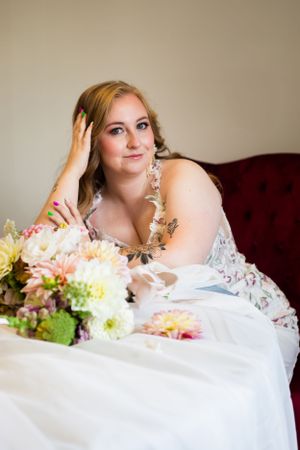A romantic bridal portrait series featuring soft white fabric and delicate floral arrangements.
