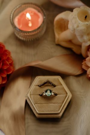 Vintage-style engagement rings displayed in hexagonal velvet ring boxes with lit candles.
