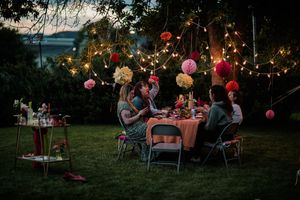 Evening garden party with glowing string lights and colorful paper lanterns hanging overhead.