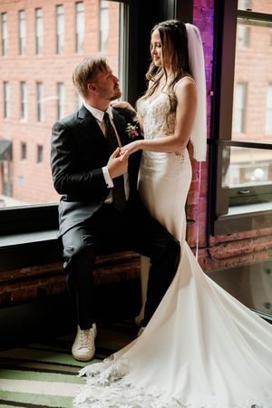 A tender wedding moment captured by large windows in an industrial-style venue.