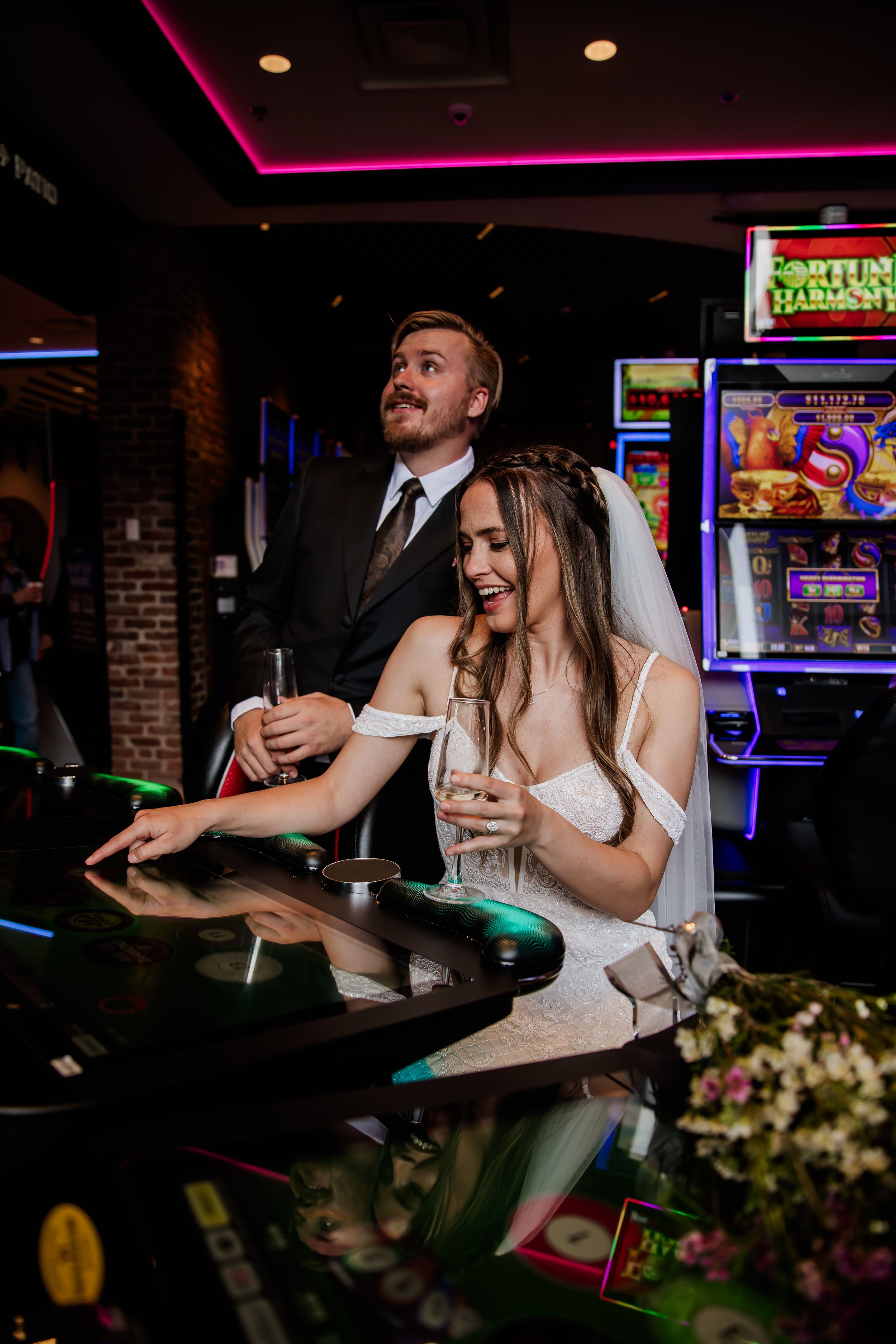 A playful wedding moment at an arcade with slot machines and neon lights.