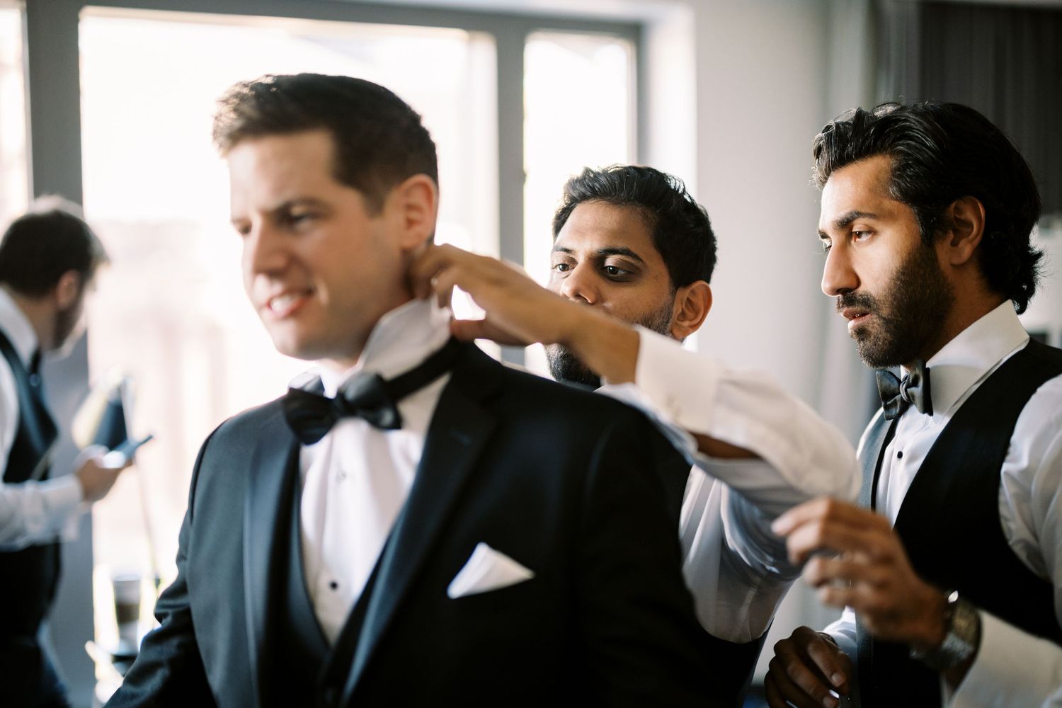 Groomsmen getting ready before wedding ceremony in formal attire with bow ties.