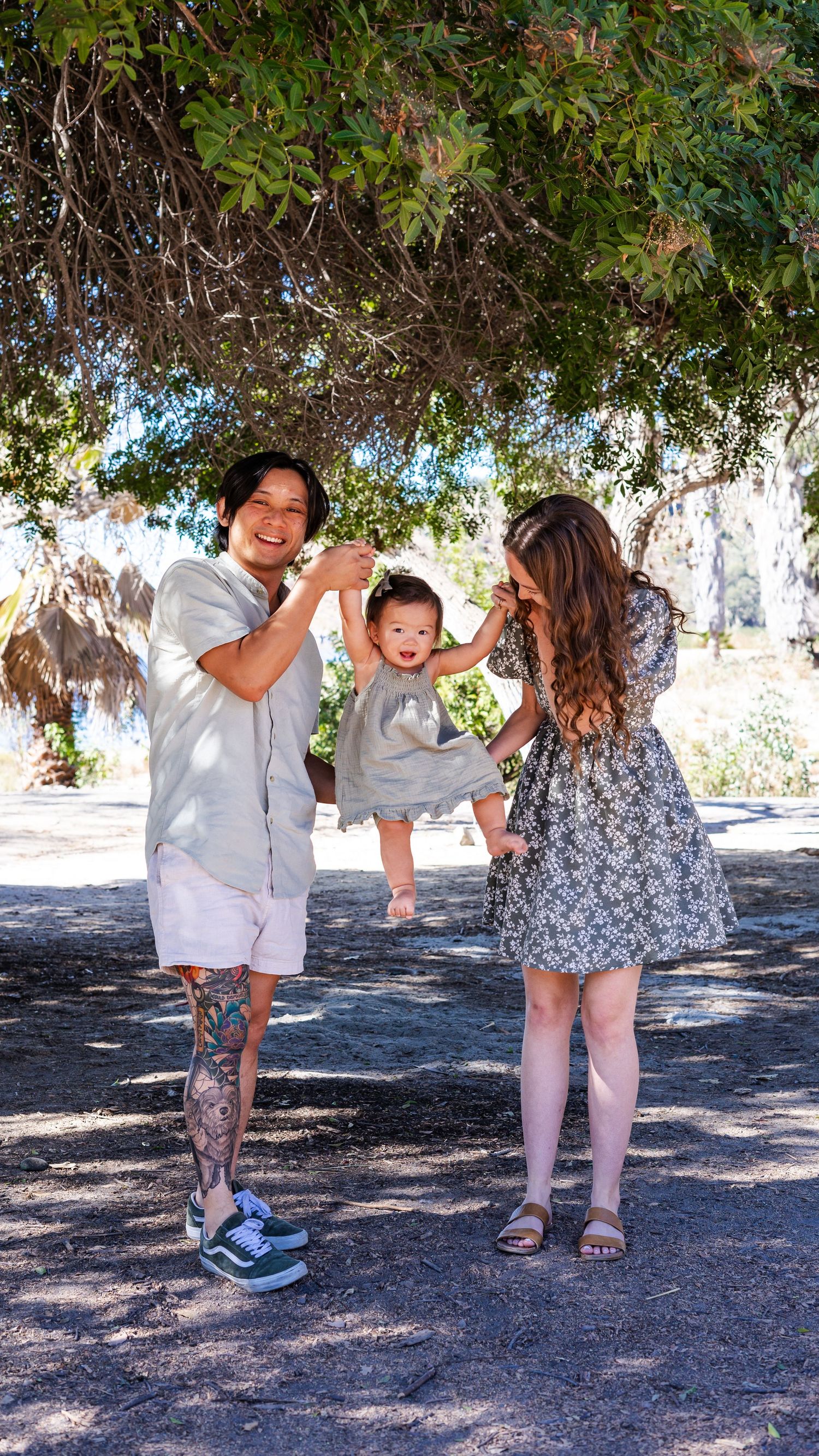 a photo of mother, father and baby under a tree